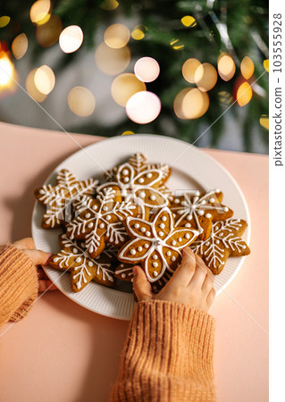 Ginger Christmas cookies in children's hands on the background of the Christmas tree. 103555928
