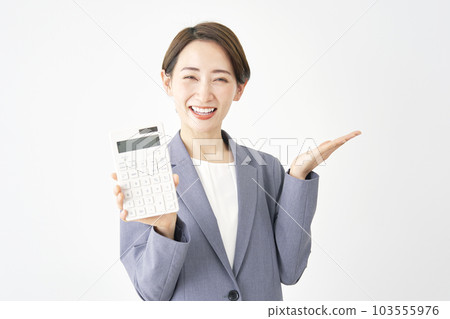 Business woman holding a calculator and pointing to the right with her palm White background Business woman holding a calculator and pointing to the right with her palm White background 103555976