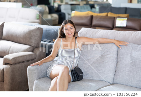 Smiling girl choosing upholstered furniture for home in store 103556224