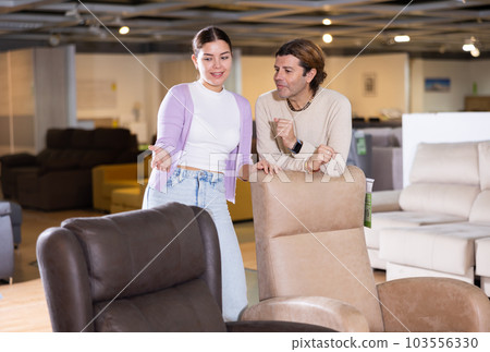 Man and woman looking to buy armchair in furniture store 103556330