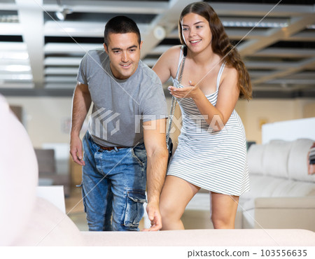 Positive couple choosing new furniture for apartment in store 103556635