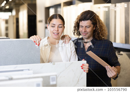 in construction department, male builder with wife choose facing plates for apartment repairs 103556790