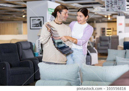 Cheerful couple deciding on material for couch in furniture store Cheerful couple deciding on material for couch in furniture store 103556816