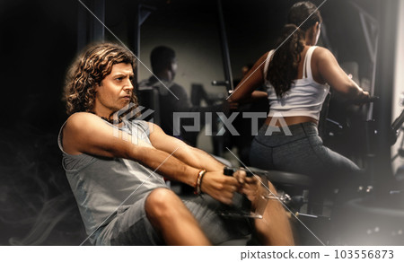 Caucasian man doing exercises on cable row machine in gym Caucasian man doing exercises on cable row machine in gym 103556873