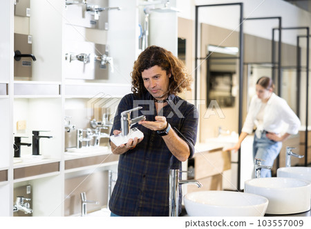 Confident man picking out new bathroom faucet in store Confident man picking out new bathroom faucet in store 103557009