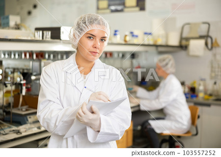 Female scientist engaged in research in chemical laboratory noting results in chart Female scientist engaged in research in chemical laboratory noting results in chart 103557252