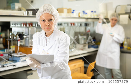 Professional scientist middle-aged woman writing notes or research report during experiment in science laboratory Professional scientist middle-aged woman writing notes or research report during experiment in science laboratory 103557279