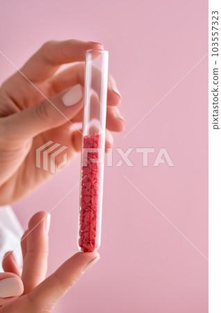 The girl is holding a test tube with red hearts. The girl is holding a test tube with red hearts. 103557323