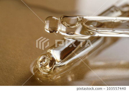 Pipettes with oil or serum on a golden background. 103557440