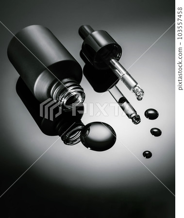 Black cosmetic bottle with dropper on black background. 103557458
