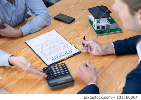 Real estate agent calculating tax and interest with calculator. Entity Real estate agent calculating tax and interest with calculator. Entity 103560064