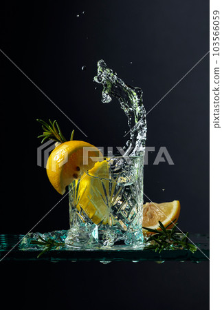 Cocktail gin-tonic with lemon and rosemary on a glass table. 103566059