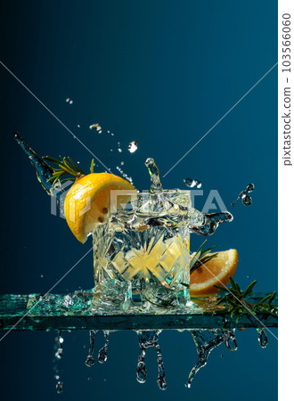 Cocktail gin-tonic with lemon and rosemary on a glass table. Cocktail gin-tonic with lemon and rosemary on a glass table. 103566060