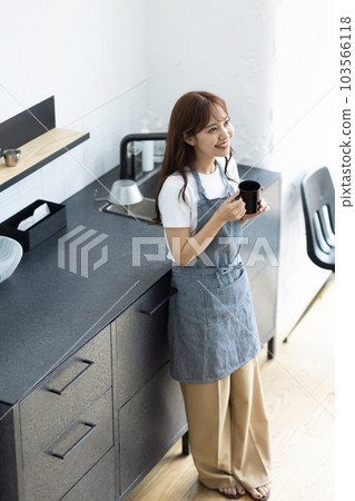 一名婦女飲用的咖啡在廚房裡 103566118