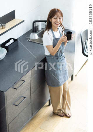 一名婦女飲用的咖啡在廚房裡 103566119
