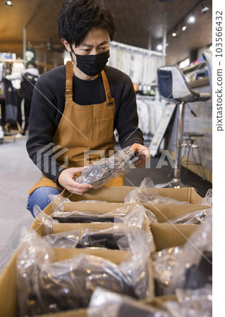 A male staff member checking the products that have arrived at the store 103566432