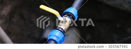 Pvc pipes with tap in ground on garden plot closeup 103567391