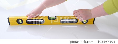 Working hands check evenness of wall with special tool for measuring level 103567394