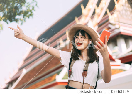 Young adult asian woman listen online streaming music and traveling at outdoor on day. 103568129