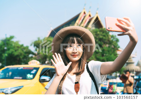 Young adult tourist asian woman using smart phone for selfie with temple background at outdoor 103568157