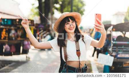 Young adult tourist asian woman using smart phone for selfie with temple background at outdoor on day Young adult tourist asian woman using smart phone for selfie with temple background at outdoor on day 103568171