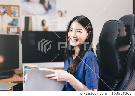 Portrait of smile young adult southeast asian woman stay at home office reading a book 103568305