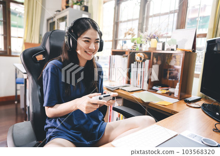 Young adult asian woman hand holding a joy controller wear headset and play game at home 103568320