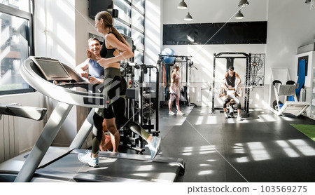 Athletic woman running on treadmill in contemporary gym Athletic woman running on treadmill in contemporary gym 103569275