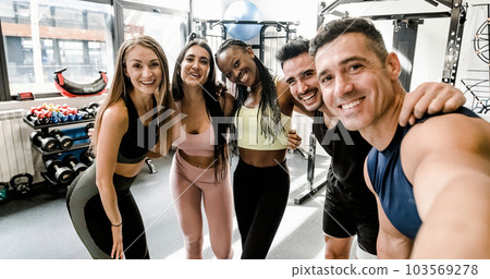 Cheerful diverse sportspeople doing selfie at gym 103569278