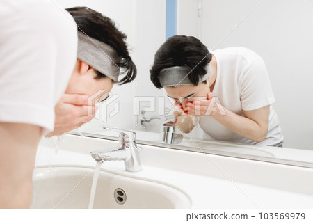 A man washing his face 103569979