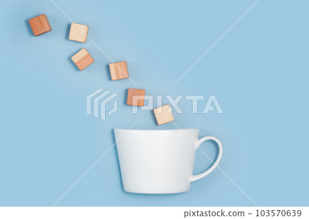 blank wooden cubes falling into a white cup on blue background. Minimalistic abstract concept representation of building creating and diversity. Top view flat lay copy space blank wooden cubes falling into a white cup on blue background. Minimalistic abstract concept representation of building creating and diversity. Top view flat lay copy space 103570639