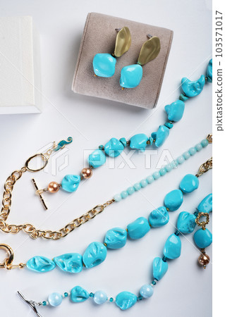 author collection jewelry with azure gemstones, pearls and chain demonstrated at white background.  fashion and jewelry concept. flat lay 103571017
