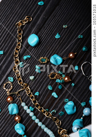 author collection jewelry with azure gemstones, pearls and chain demonstrated at black stones background. fashion and jewelry concept. flat lay author collection jewelry with azure gemstones, pearls and chain demonstrated at black stones background. fashion and jewelry concept. flat lay 103571018