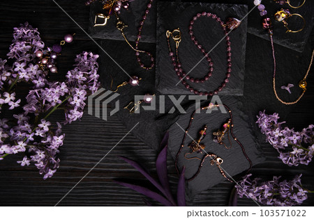 author collection jewelry with lilac gemstones, crystals and pearls demonstrated at black stones background. fashion and jewelry concept. flat lay author collection jewelry with lilac gemstones, crystals and pearls demonstrated at black stones background. fashion and jewelry concept. flat lay 103571022