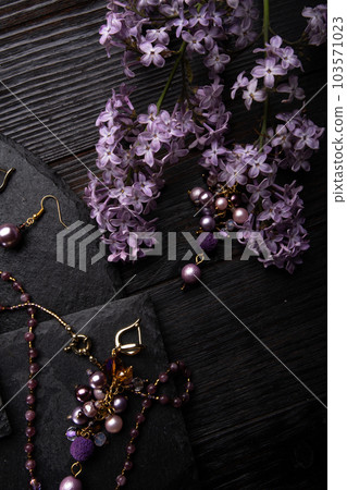 author collection jewelry with lilac gemstones, crystals  and pearls demonstrated at black stones background.  fashion and jewelry concept. flat lay 103571023