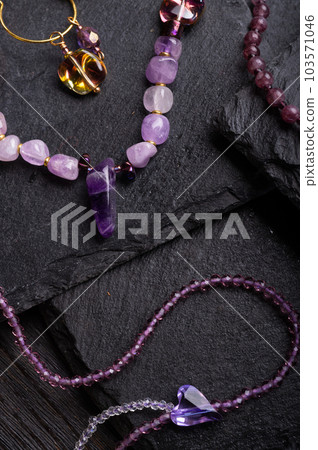 author collection jewelry with lilac gemstones, crystals demonstrated at black stones background. fashion and jewelry concept. flat lay. macro shot author collection jewelry with lilac gemstones, crystals demonstrated at black stones background. fashion and jewelry concept. flat lay. macro shot 103571046