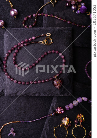 author collection jewelry with lilac gemstones, crystals and pearls demonstrated at black stones background. fashion and jewelry concept. flat lay author collection jewelry with lilac gemstones, crystals and pearls demonstrated at black stones background. fashion and jewelry concept. flat lay 103571052