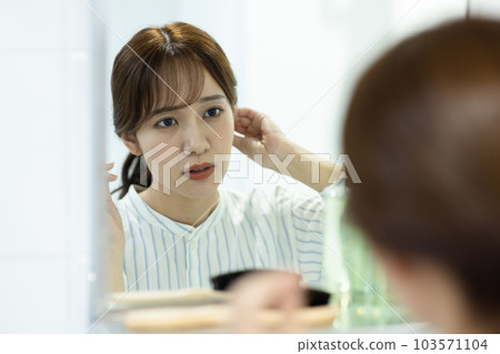 A woman troubled watching a mirror A woman troubled watching a mirror 103571104