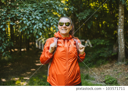 Young happy 30s woman hiking and going camping in nature. Person with backpack walking in the forest 103571711
