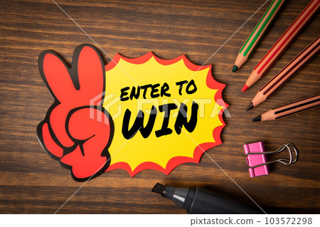 Enter to Win. Text on sticky note, wooden office desk Enter to Win. Text on sticky note, wooden office desk 103572298