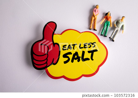 Eat Less Salt. Sticky note with text and miniature human figures on a white background Eat Less Salt. Sticky note with text and miniature human figures on a white background 103572316