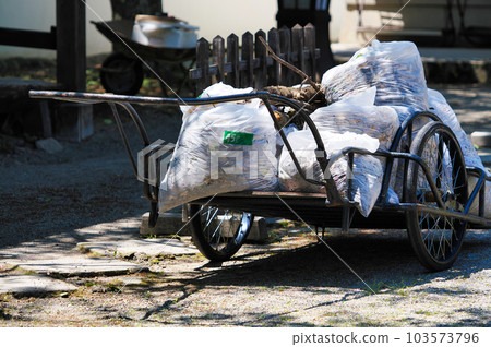 A cart loaded with garbage bags containing fallen leaves A cart loaded with garbage bags containing fallen leaves 103573796