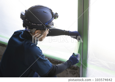 A worker man masking with curing tape at a construction site A worker man masking with curing tape at a construction site 103574642