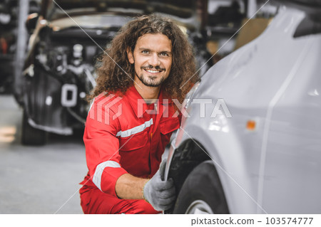 Hispanic male staff worker work in auto workshop happy smiling enjoy working servicing car tire replace 103574777