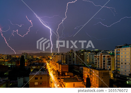 Lightning storm over city in purple light 103576072