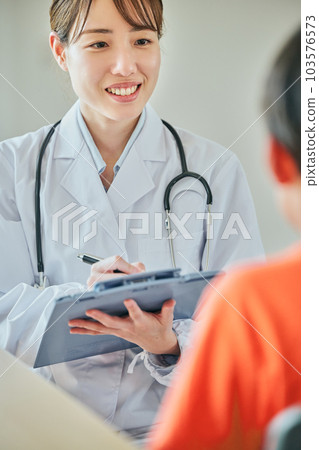 A young female doctor interviewing an elementary school boy 103576573
