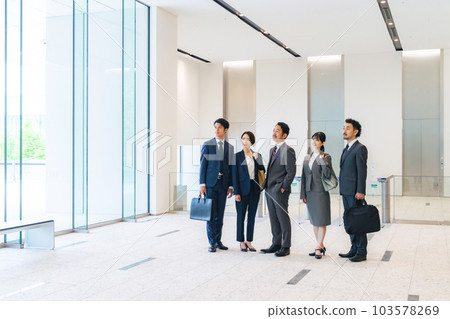 Group of business people looking up at the sky in the office building lobby Group of business people looking up at the sky in the office building lobby 103578269