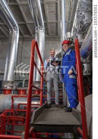 Smiling Manager With Digital Tablet Standing Next to Worker in Power Plant Smiling Manager With Digital Tablet Standing Next to Worker in Power Plant 103578501