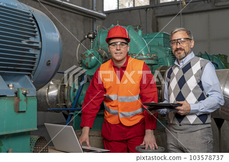 Young Worker Using Laptop Computer for Data Checking With Technical Manager in Power Plant 103578737
