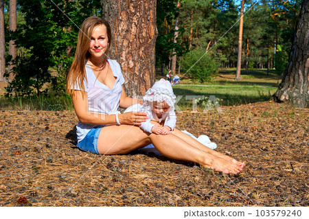 Young happy mother with a cute breast newborn baby in a sunny forest Young happy mother with a cute breast newborn baby in a sunny forest 103579240